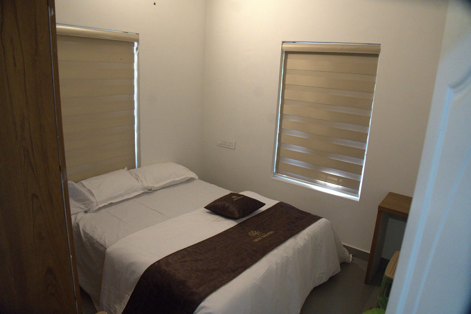 Bedroom with a neatly made bed and blinded window
