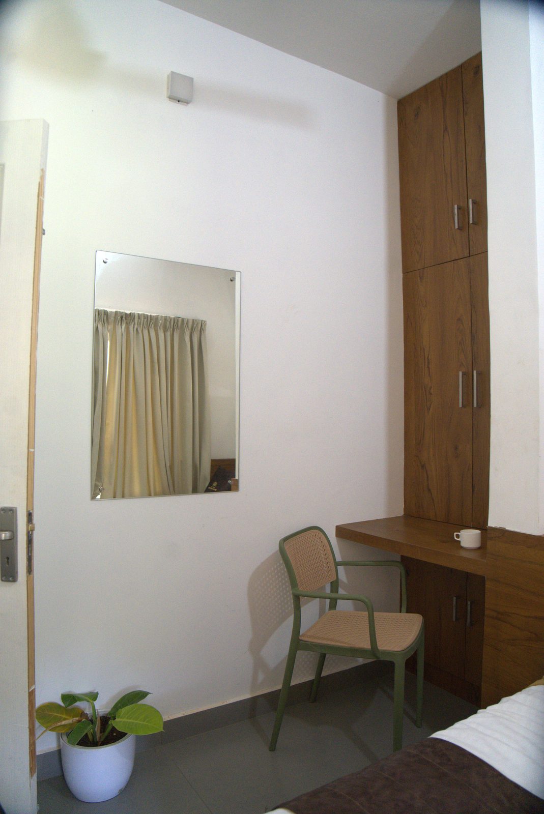 Room corner with a mirror, a wooden wardrobe and a green chair