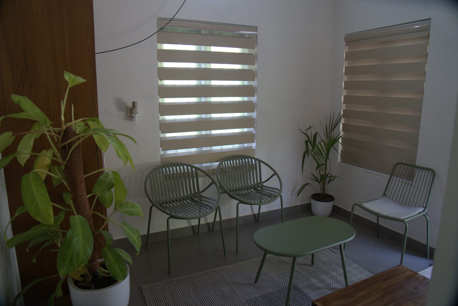 Sitting area with green metal chairs, a low table and indoor plants