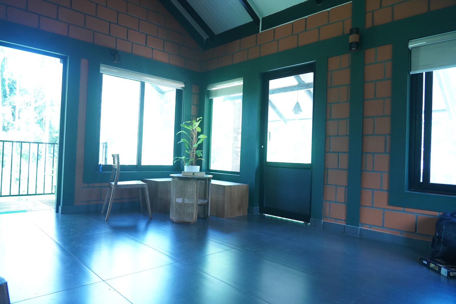 Bright sun-room with large windows, brick walls and a glossy floor